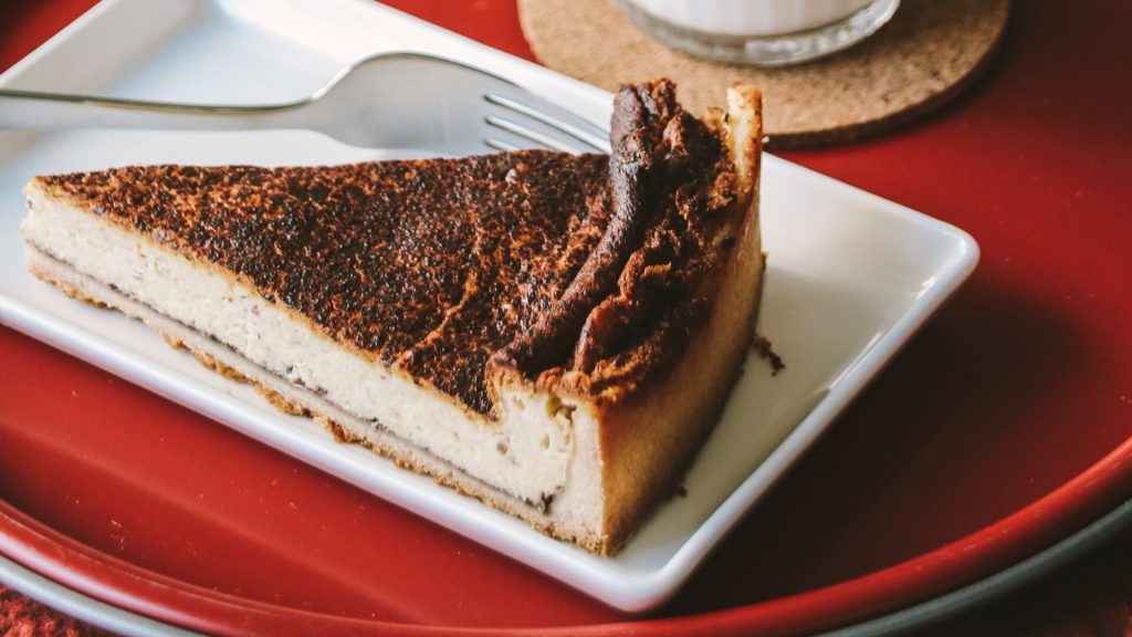 Una fetta di cheesecake cremosa al sapore di caffè con una crosta di biscotti